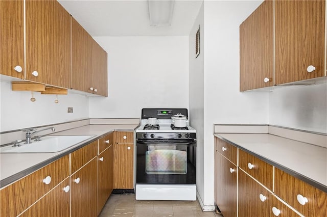333 Pearl St Unit 8E, New York, NY 10038 - kitchen featuring gas range, brown cabinetry, and light tile patterned floors