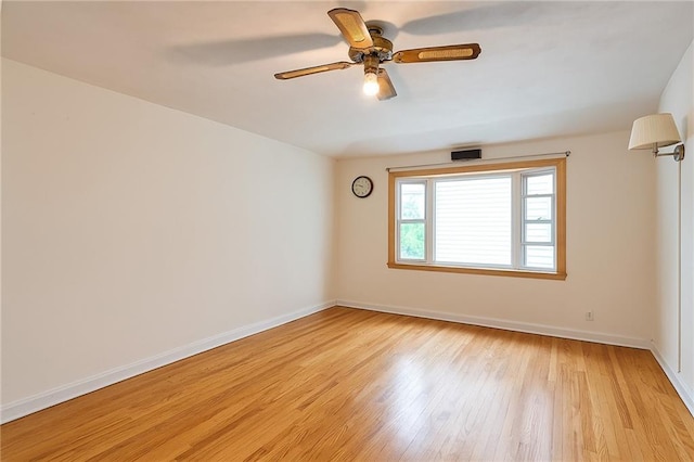 spare room with baseboards, light wood-style flooring, and a ceiling fan