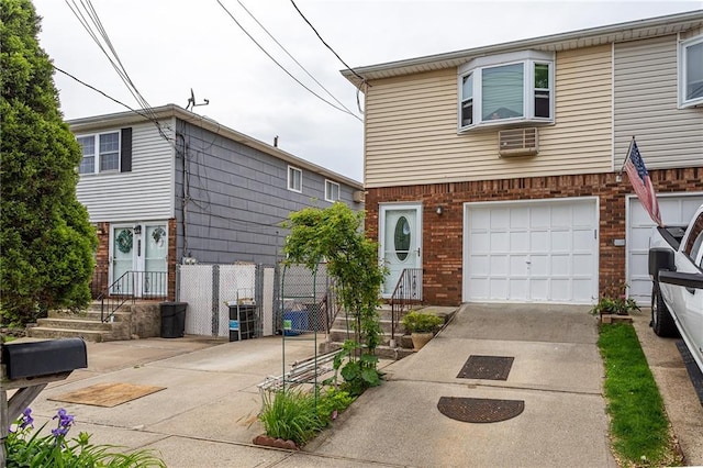 view of front of property with brick siding, an attached garage, driveway, and a wall unit AC