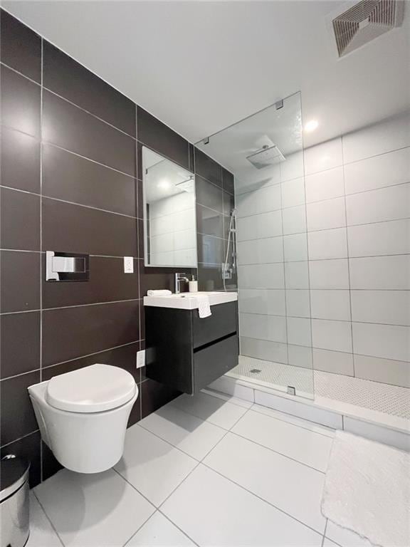 bathroom with toilet, a walk in shower, tile walls, vanity, and tile patterned floors