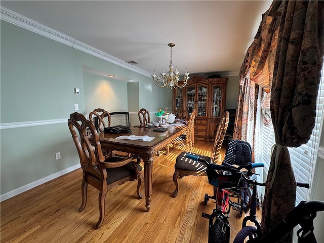 dining room with ornamental molding, wood finished floors, a chandelier, and baseboards
