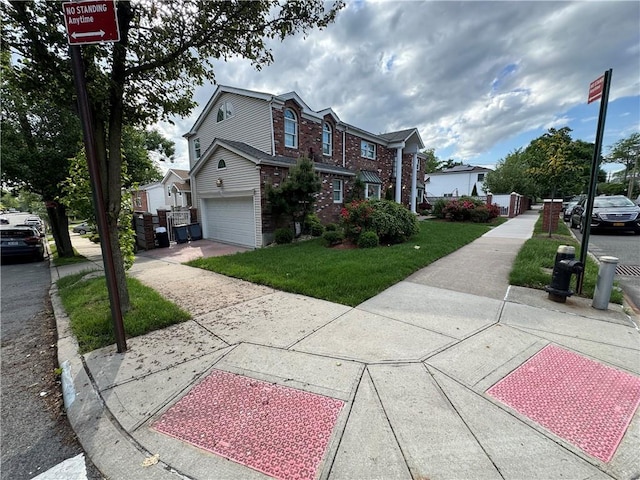 view of front of home with a garage, brick siding, driveway, a front yard, and a residential view