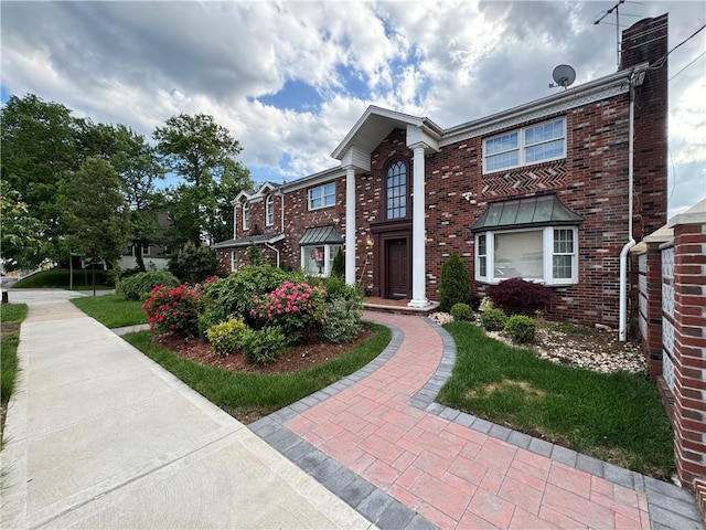 view of front of house with brick siding and a chimney