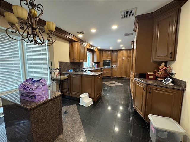 kitchen with stainless steel oven, a chandelier, a peninsula, granite floors, and recessed lighting