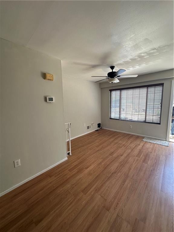 unfurnished room with wood finished floors, ceiling fan, and baseboards