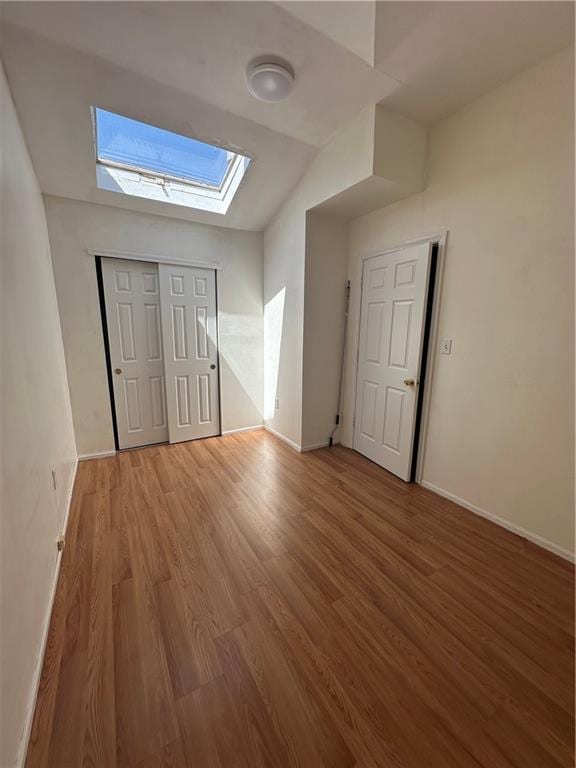 entrance foyer with a skylight, wood finished floors, and baseboards