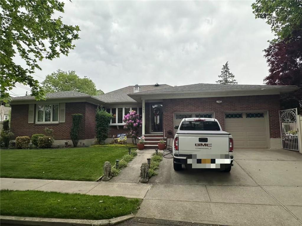 single story home with driveway, brick siding, an attached garage, and a front yard