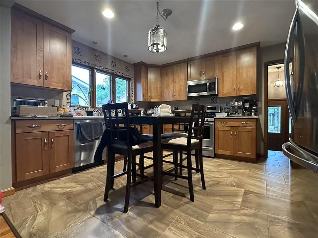 kitchen featuring stainless steel appliances, brown cabinets, pendant lighting, and recessed lighting