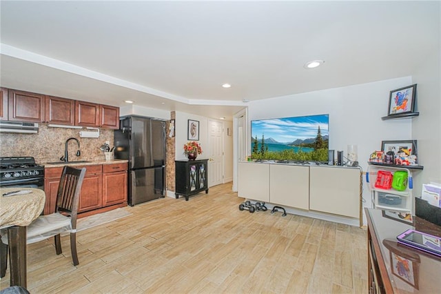 30-30 78th St, Queens, NY 11370 - kitchen with freestanding refrigerator, under cabinet range hood, black gas range, a sink, and light wood-style floors