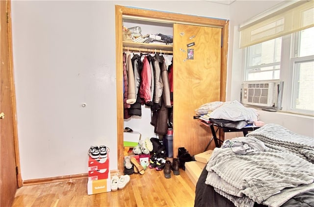 bedroom with wood finished floors, a closet, cooling unit, and baseboards