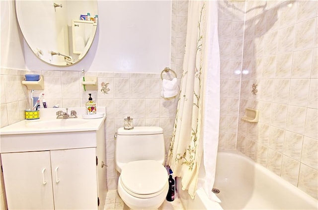 full bathroom with toilet, vanity, shower / bath combo with shower curtain, tile walls, and wainscoting