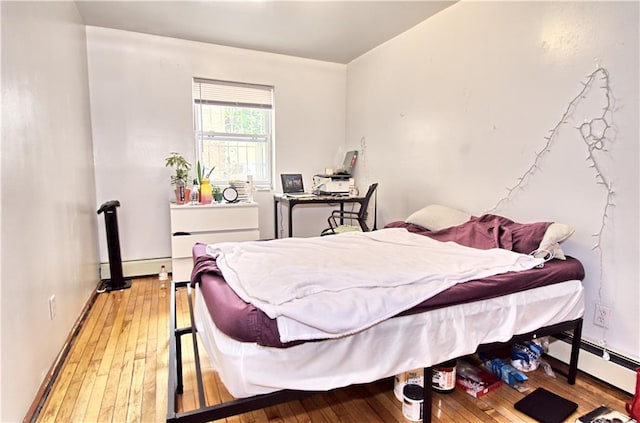 bedroom featuring light wood-style flooring, baseboard heating, and baseboards