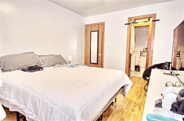 bedroom with light wood-style flooring and connected bathroom