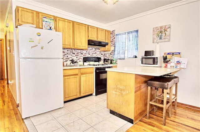 kitchen featuring white appliances, under cabinet range hood, light countertops, ornamental molding, and decorative backsplash