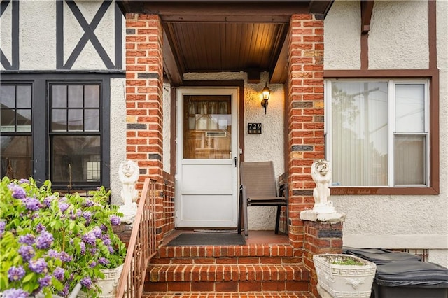 doorway to property featuring stucco siding and brick siding