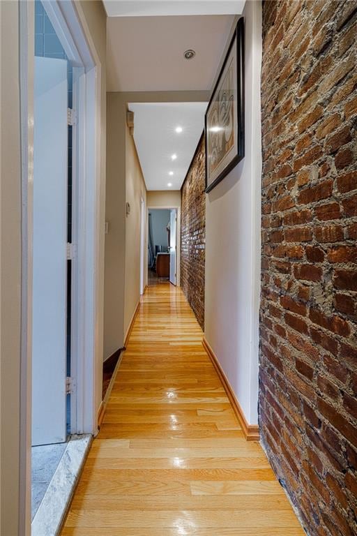 2077 E 22nd St, Brooklyn, NY 11229 - corridor with light wood finished floors, brick wall, and baseboards