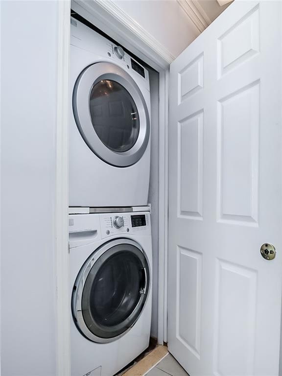 139 Tennyson Dr, Staten Island, NY 10308 - laundry area with stacked washer and clothes dryer and light tile patterned floors