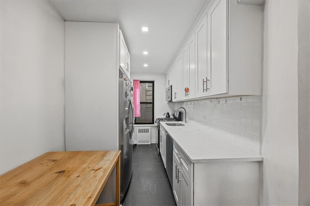 9040 Fort Hamilton Pkwy Unit 2I, Brooklyn, NY 11209 - kitchen featuring appliances with stainless steel finishes, tasteful backsplash, white cabinetry, radiator, and a sink