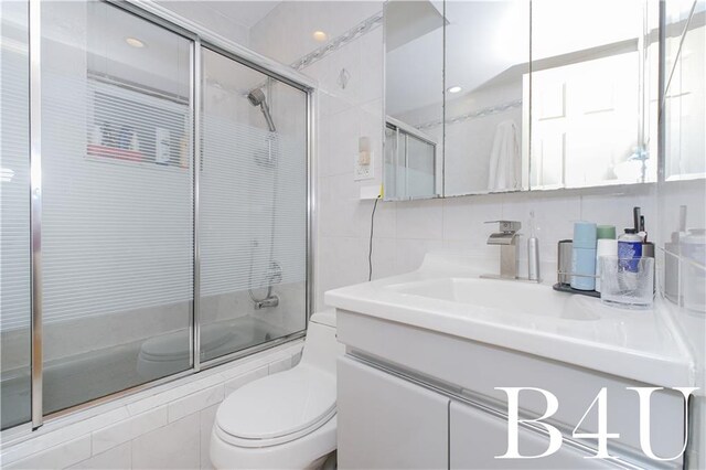 2544 E 64th St, Brooklyn, NY 11234 - bathroom featuring tile walls, vanity, tiled shower / bath, toilet, and decorative backsplash