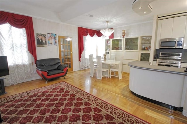 119 Langham St, Brooklyn, NY 11235 - kitchen with appliances with stainless steel finishes, a chandelier, crown molding, pendant lighting, and white cabinetry