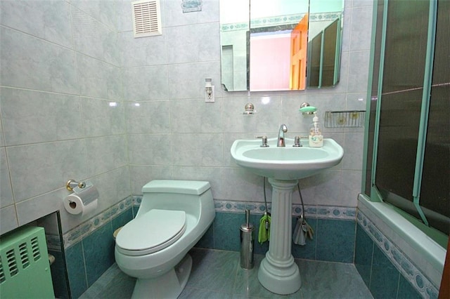 119 Langham St, Brooklyn, NY 11235 - full bath with tile walls, radiator heating unit, and tiled shower / bath combo
