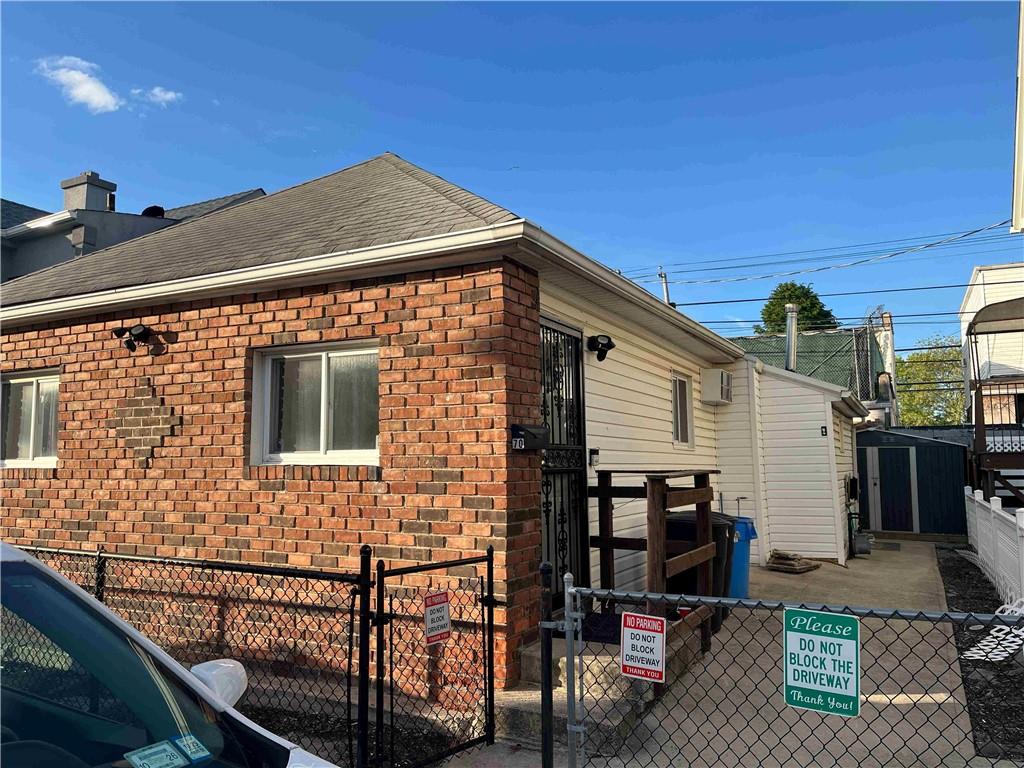 70 Aster Ct, Brooklyn, NY 11229 - view of side of property with a gate, brick siding, and roof with shingles