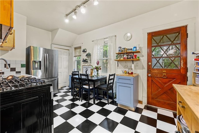 701 127th St, Queens, NY 11356 - kitchen with dark floors, stainless steel fridge, open shelves, wood counters, and track lighting