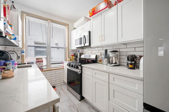 1436 78th St, Brooklyn, NY 11228 - kitchen with appliances with stainless steel finishes, white cabinetry, light marble finish flooring, decorative backsplash, and light stone countertops