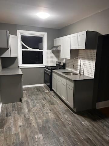 79 Mundy Ave, Staten Island, NY 10310 - kitchen with range with gas cooktop, a sink, ventilation hood, dark wood finished floors, and decorative backsplash