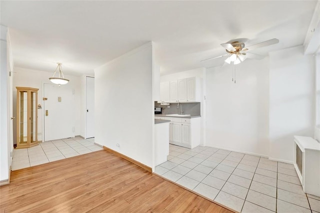2483 W 16th St Unit 10K, Brooklyn, NY 11214 - kitchen with light wood-style floors, white cabinets, a ceiling fan, light countertops, and hanging light fixtures