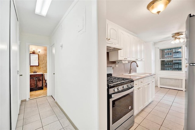 2483 W 16th St Unit 10K, Brooklyn, NY 11214 - kitchen with gas range, under cabinet range hood, light tile patterned flooring, white cabinets, and a ceiling fan