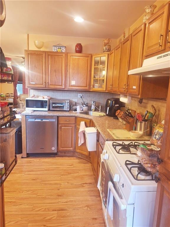 1675 72nd St, Brooklyn, NY 11204 - kitchen with stainless steel appliances, under cabinet range hood, light wood-type flooring, decorative backsplash, and brown cabinetry