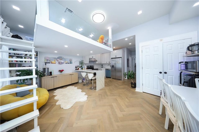 4 Lake Ave, Brooklyn, NY 11235 - kitchen featuring stainless steel appliances, a kitchen breakfast bar, under cabinet range hood, light countertops, and white cabinetry