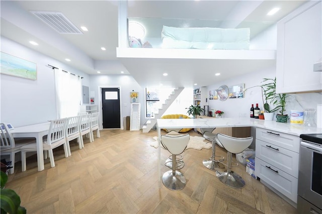 4 Lake Ave, Brooklyn, NY 11235 - kitchen featuring electric stove, a peninsula, white cabinets, recessed lighting, and a kitchen breakfast bar