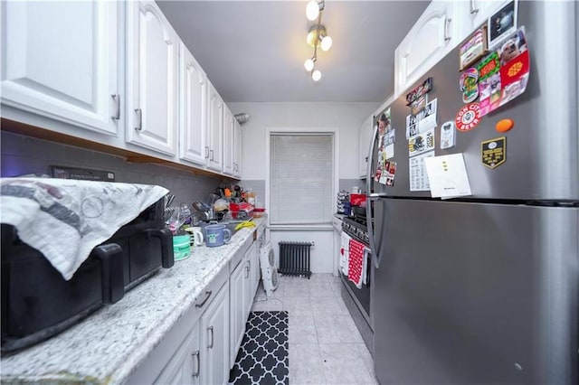 1711 Bay Ridge Parkway, Brooklyn, NY 11204 - kitchen featuring stainless steel appliances, radiator, white cabinets, light tile patterned floors, and light stone countertops
