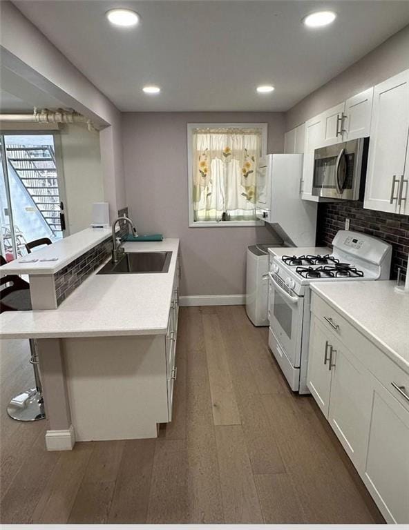 1711 Bay Ridge Parkway, Brooklyn, NY 11204 - kitchen with white gas range oven, stainless steel microwave, a sink, baseboards, and a peninsula