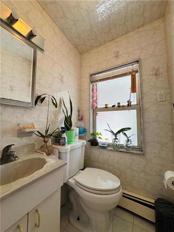 1414 76th St, Brooklyn, NY 11228 - bathroom featuring a baseboard heating unit, tile walls, tile patterned floors, toilet, and vanity
