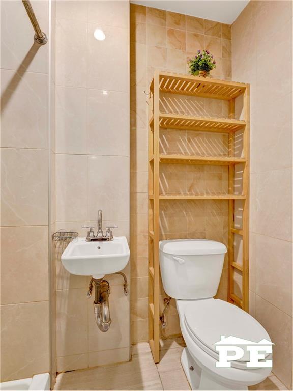 2077 Hendrickson St, Brooklyn, NY 11234 - bathroom with tile walls, toilet, and a sink