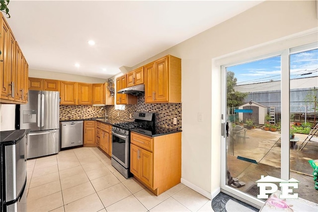 2077 Hendrickson St, Brooklyn, NY 11234 - kitchen with appliances with stainless steel finishes, dark countertops, backsplash, under cabinet range hood, and light tile patterned floors