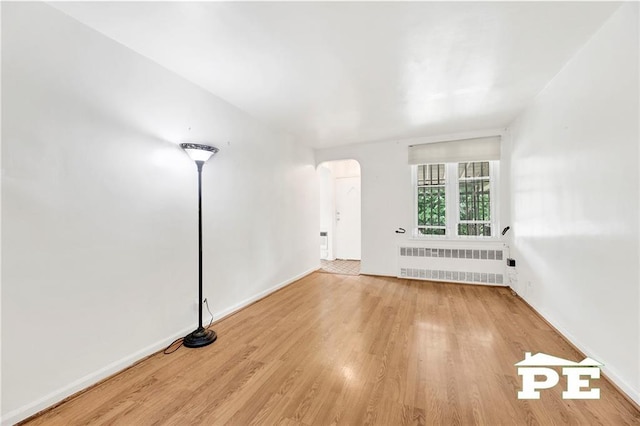 5709 Fillmore Ave, Brooklyn, NY 11234 - unfurnished room with radiator heating unit, arched walkways, wood finished floors, and baseboards