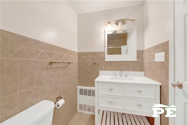5709 Fillmore Ave, Brooklyn, NY 11234 - bathroom with radiator, tile walls, vanity, toilet, and a wainscoted wall