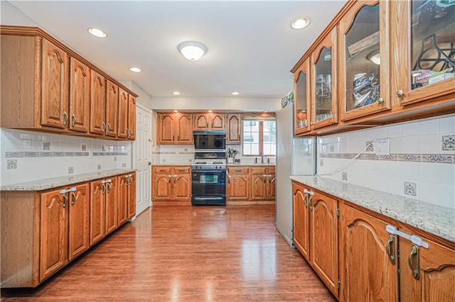 39 Morton St, Staten Island, NY 10306 - kitchen featuring gas range oven, decorative backsplash, brown cabinets, light wood-style floors, and light stone counters