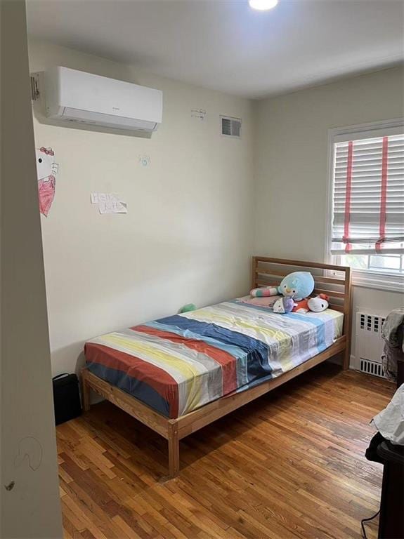 1711 E 36th St, Brooklyn, NY 11234 - bedroom featuring a wall mounted air conditioner, radiator heating unit, and wood finished floors