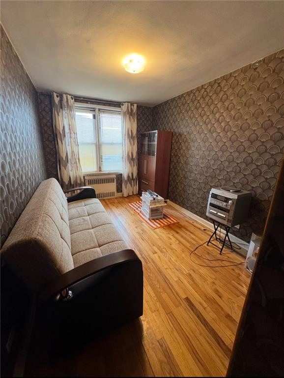 1811 Ocean Pkwy Unit 6-L, Brooklyn, NY 11223 - sitting room featuring wallpapered walls, radiator heating unit, and wood finished floors