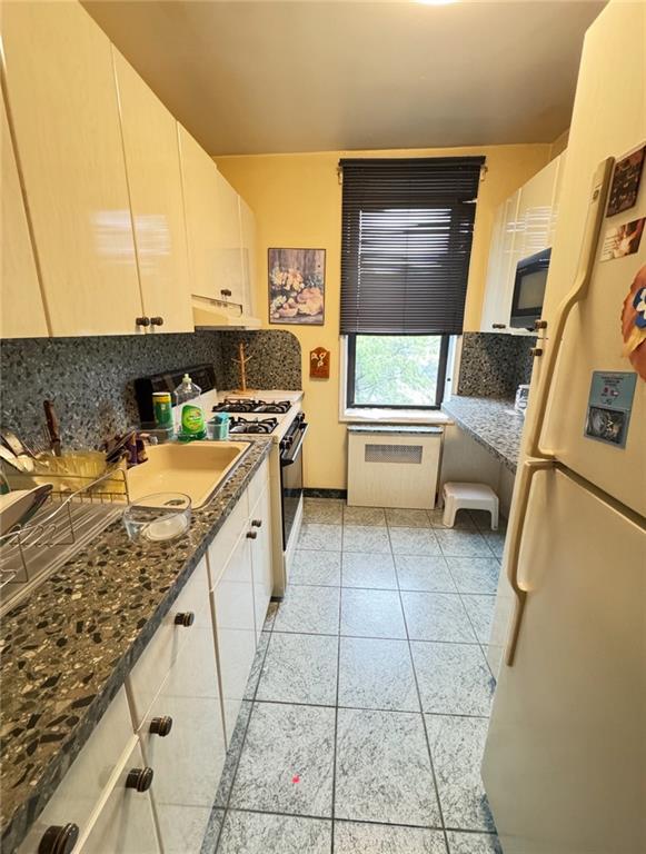 1811 Ocean Pkwy Unit 6-L, Brooklyn, NY 11223 - kitchen with freestanding refrigerator, tasteful backsplash, range with gas stovetop, under cabinet range hood, and white cabinets