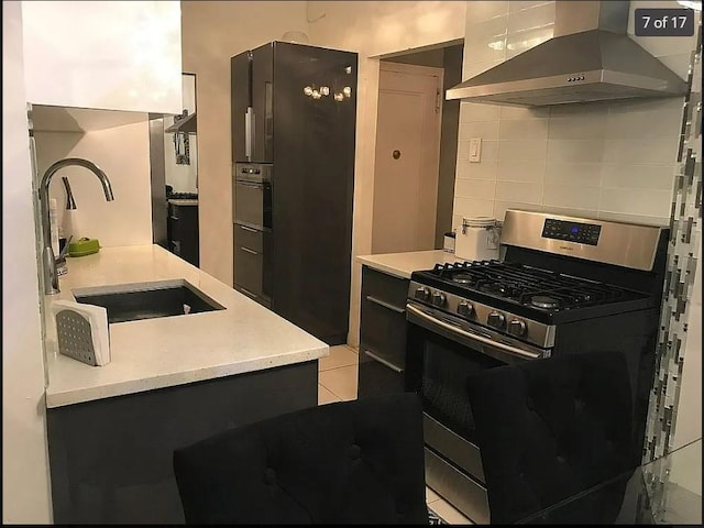 1440 Midland Ave Unit 1D, Bronxville, NY 10108 - kitchen with wall chimney range hood, gas stove, a sink, decorative backsplash, and light countertops