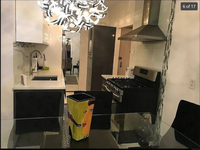 1440 Midland Ave Unit 1D, Bronxville, NY 10108 - kitchen featuring wall chimney range hood, a sink, a chandelier, backsplash, and gas stove