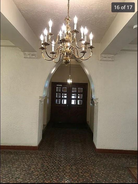 1440 Midland Ave Unit 1D, Bronxville, NY 10108 - hall featuring arched walkways, a chandelier, a textured ceiling, baseboards, and a textured wall