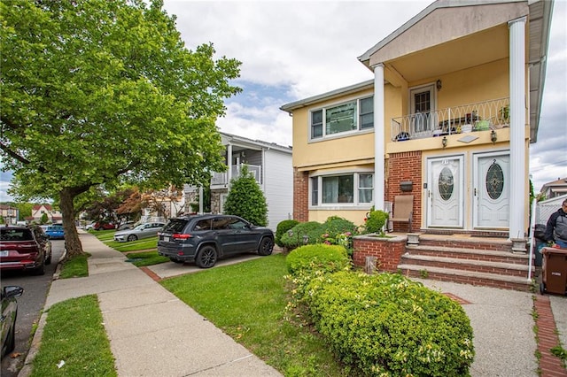 27 Bascom Pl, Staten Island, NY 10314 - view of front of house featuring stucco siding, a balcony, and brick siding