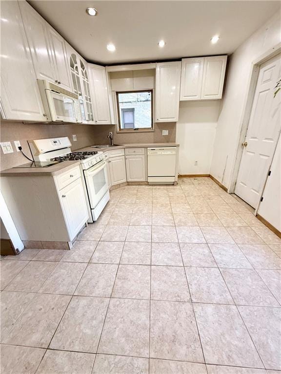 133 Quentin Rd, Brooklyn, NY 11223 - kitchen with white appliances, glass insert cabinets, a sink, light tile patterned floors, and baseboards